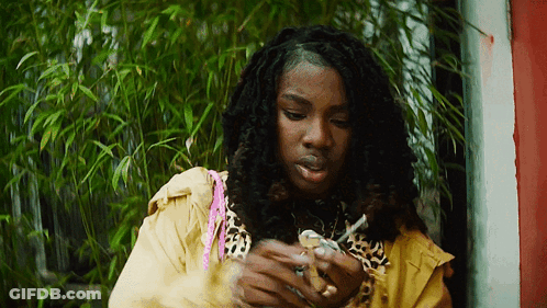 A Woman In A Leopard Print Jacket Is Smoking A Cigarette . GIF