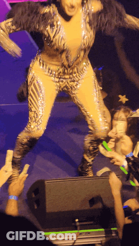 A Woman In A Leopard Print Jumpsuit Is Dancing On Stage GIF