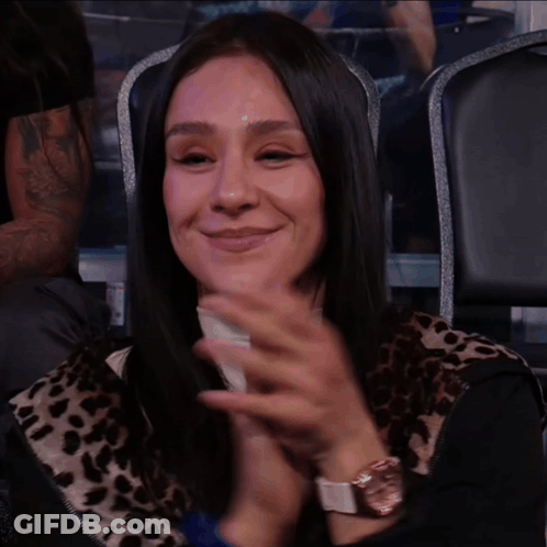 A Woman In A Leopard Print Shirt Is Smiling And Clapping GIF