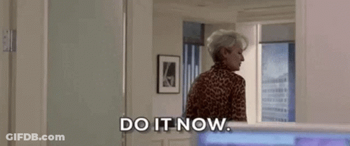 A Woman In A Leopard Print Shirt Is Standing In A Room . GIF