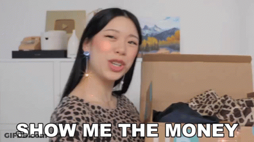 A Woman In A Leopard Print Shirt Is Standing In Front Of A Cardboard Box That Says Show Me The Money GIF