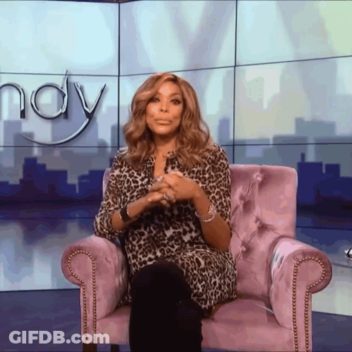 A Woman In A Leopard Print Shirt Sits In A Purple Chair In Front Of A Wall That Says Wendy GIF