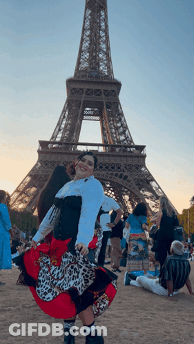 A Woman In A Leopard Print Skirt Is Posing In Front Of The Eiffel Tower GIF