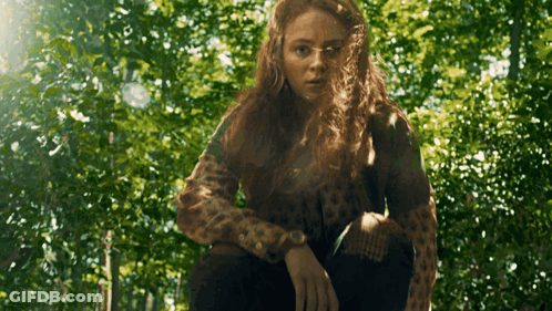 A Woman In A Leopard Print Sweater Is Standing In The Woods GIF