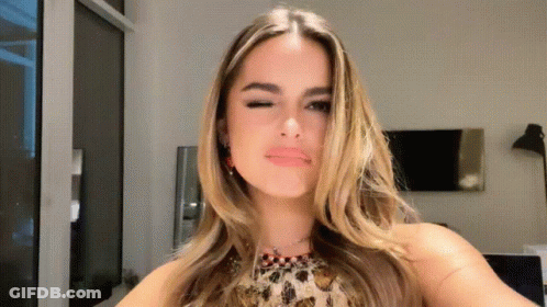 A Woman In A Leopard Print Top Is Taking A Selfie GIF