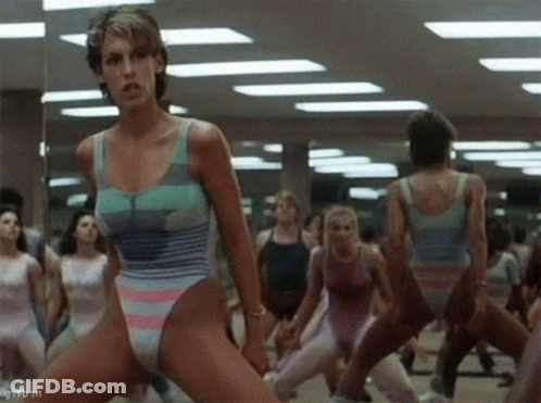 A Woman In A Leotard Is Dancing In A Gym With Other Women GIF