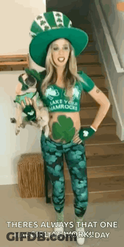A Woman In A Leprechaun Costume Is Standing On A Set Of Stairs Holding A Small Dog . GIF