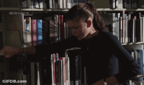 A Woman In A Library Reaches For A Book That Says Visa On The Spine GIF