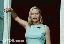 A Woman In A Light Blue Dress Is Standing In Front Of A Window . GIF