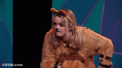 A Woman In A Lion Costume Is Sitting On A Stage With Her Hands On Her Hips . GIF