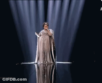 A Woman In A Long Dress Singing Into A Microphone On A Stage With The Hashtag Serbia #Srb GIF