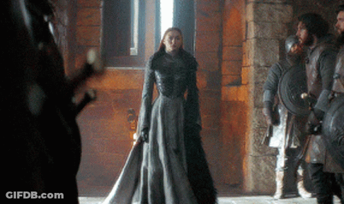 A Woman In A Long Gray Dress Is Standing In Front Of A Group Of Soldiers GIF