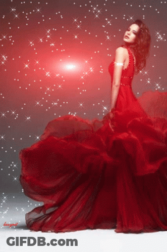 A Woman In A Long Red Dress Is Standing In Front Of A Red Background GIF