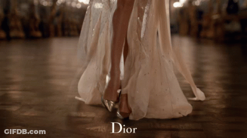 A Woman In A Long White Dress Is Dancing And The Word Dior Is On The Bottom GIF