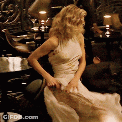A Woman In A Long White Dress Is Dancing In A Dark Room GIF