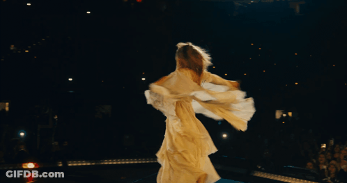 A Woman In A Long White Dress Is Dancing In The Dark GIF