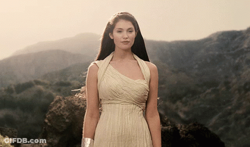 A Woman In A Long White Dress Stands In Front Of Mountains GIF
