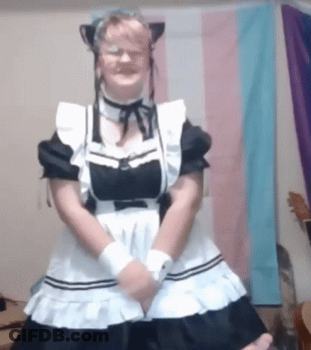 A Woman In A Maid Costume Is Standing In Front Of A Flag . GIF