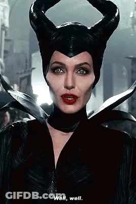 A Woman In A Maleficent Costume With Horns On Her Head Is Talking To Someone . GIF