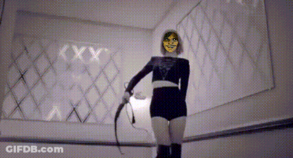 A Woman In A Mask Is Holding A Whip In Front Of A Mirror . GIF