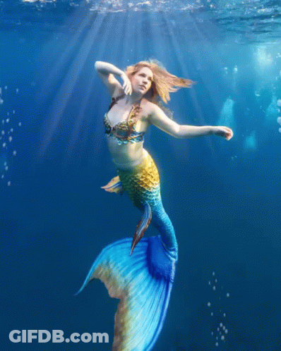 A Woman In A Mermaid Costume Is Swimming In The Water GIF