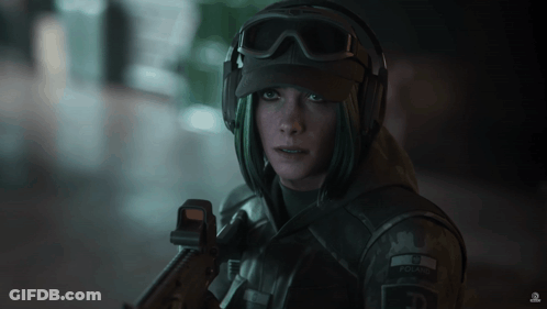 A Woman In A Military Uniform Is Holding A Gun And Has The Letter E On Her Hat GIF