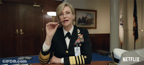 A Woman In A Military Uniform Is Sitting At A Desk With A Netflix Logo In The Background GIF