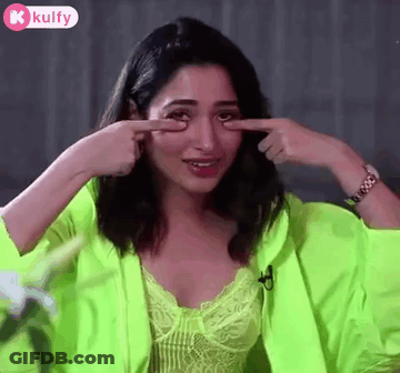 A Woman In A Neon Green Jacket Is Pointing At Her Eye . GIF