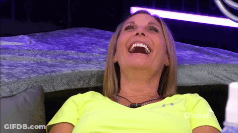 A Woman In A Neon Yellow Shirt Is Laughing On A Couch GIF