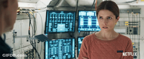 A Woman In A Netflix Sweater Stands In Front Of A Bunch Of Monitors GIF