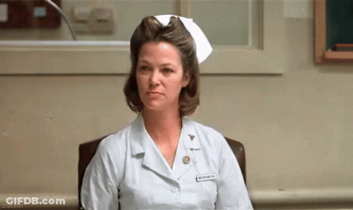 A Woman In A Nurse 'S Uniform Is Sitting In A Chair . GIF