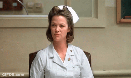 A Woman In A Nurse 'S Uniform Is Sitting In A Chair . GIF