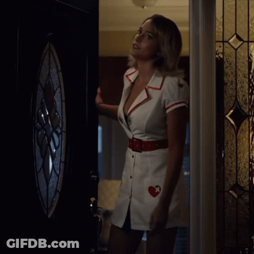 A Woman In A Nurse 'S Uniform Is Standing In A Doorway GIF