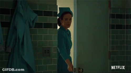 A Woman In A Nurse 'S Uniform Is Standing In A Doorway With A Netflix Logo Behind Her GIF