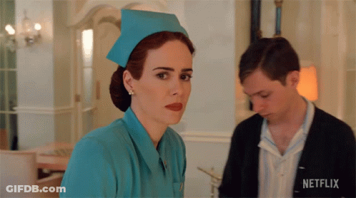 A Woman In A Nurse 'S Uniform Is Standing Next To A Man With A Netflix Logo On His Shirt GIF