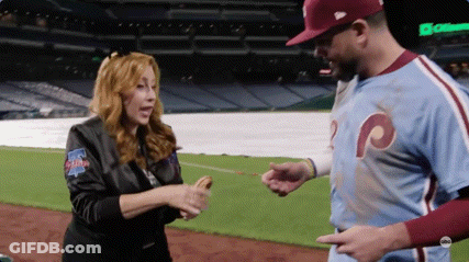 A Woman In A Phillies Jacket Is Shaking Hands With A Baseball Player GIF