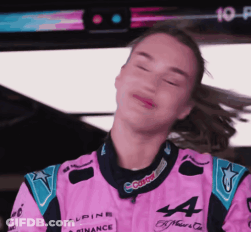 A Woman In A Pink Alpine Racing Suit Is Making A Face GIF
