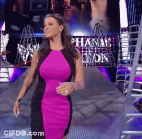A Woman In A Pink And Black Dress Is Walking Down A Ramp In Front Of A Ladder . GIF