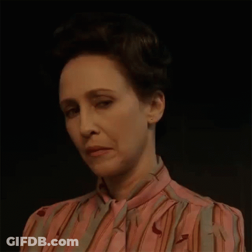 A Woman In A Pink And Gray Striped Shirt Is Making A Funny Face . GIF