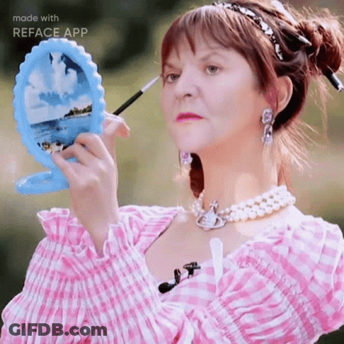 A Woman In A Pink And White Plaid Dress Is Applying Makeup GIF