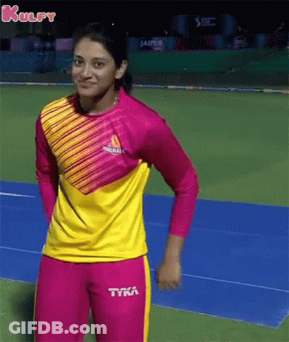 A Woman In A Pink And Yellow Striped Shirt And Pink Pants Is Standing On A Track . GIF