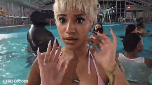 A Woman In A Pink Bikini Is Standing In A Swimming Pool With A Surprised Look On Her Face . GIF