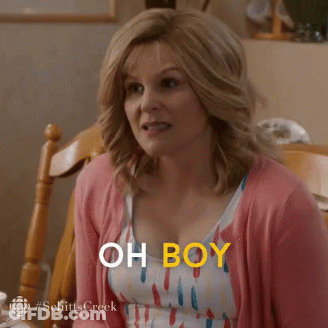 A Woman In A Pink Cardigan Is Sitting At A Table And Says `` Oh Boy '' . GIF