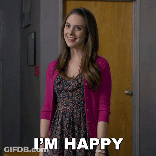 A Woman In A Pink Cardigan Says I 'M Happy In Front Of A Door GIF