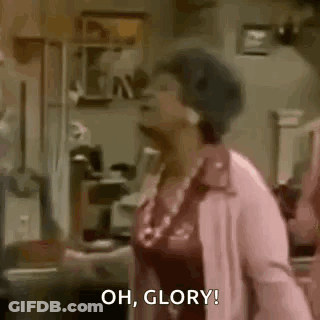 A Woman In A Pink Coat Is Standing In A Living Room . GIF