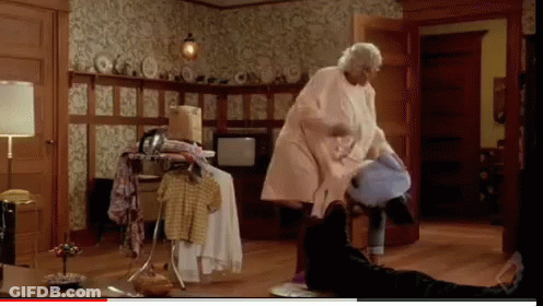 A Woman In A Pink Coat Is Standing In A Room GIF