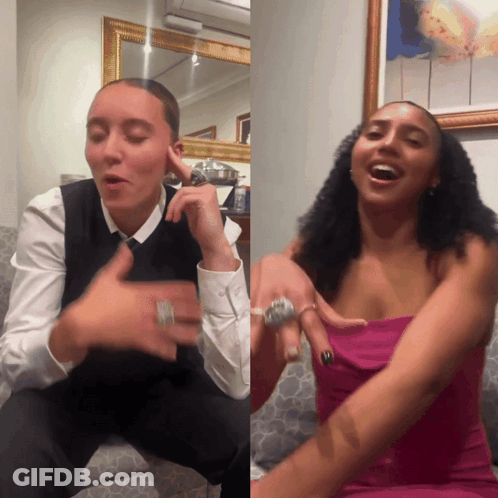 A Woman In A Pink Dress And A Man In A Black Vest Are Sitting On A Couch GIF