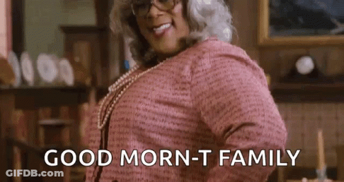 A Woman In A Pink Dress And Glasses Is Saying `` Good Morning - T Family '' . GIF