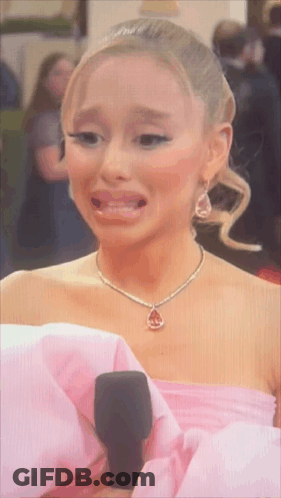 A Woman In A Pink Dress And Necklace Is Crying GIF