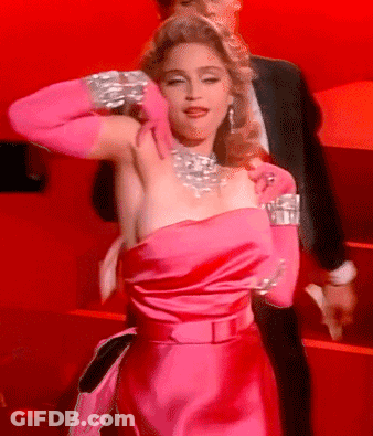 A Woman In A Pink Dress And Pink Gloves Is Standing Next To A Man In A Suit GIF